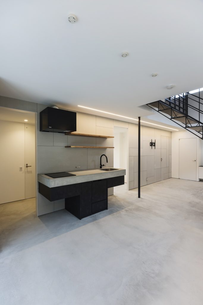 Completed professional kitchen at Sunset Villa, Awajishima — island bench, black cabinetry and concrete floor finish viewed from south corner
