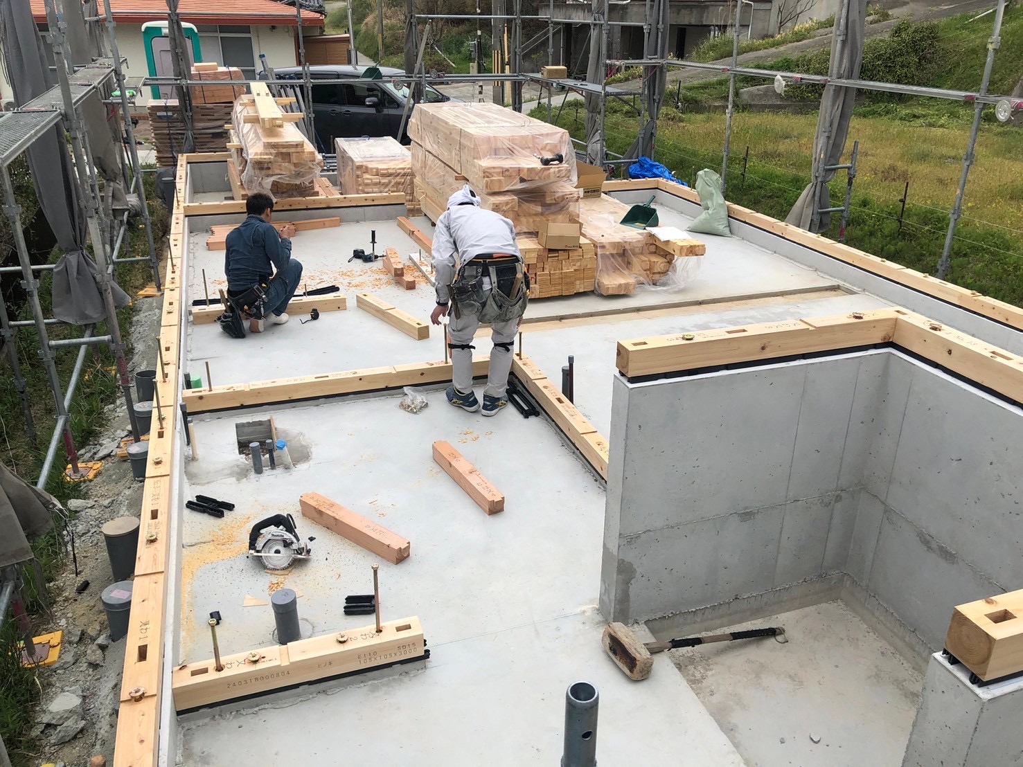 Pre-cut timber frame being assembled by carpenters on concrete foundation slab at Sunset Villa, Awajishima