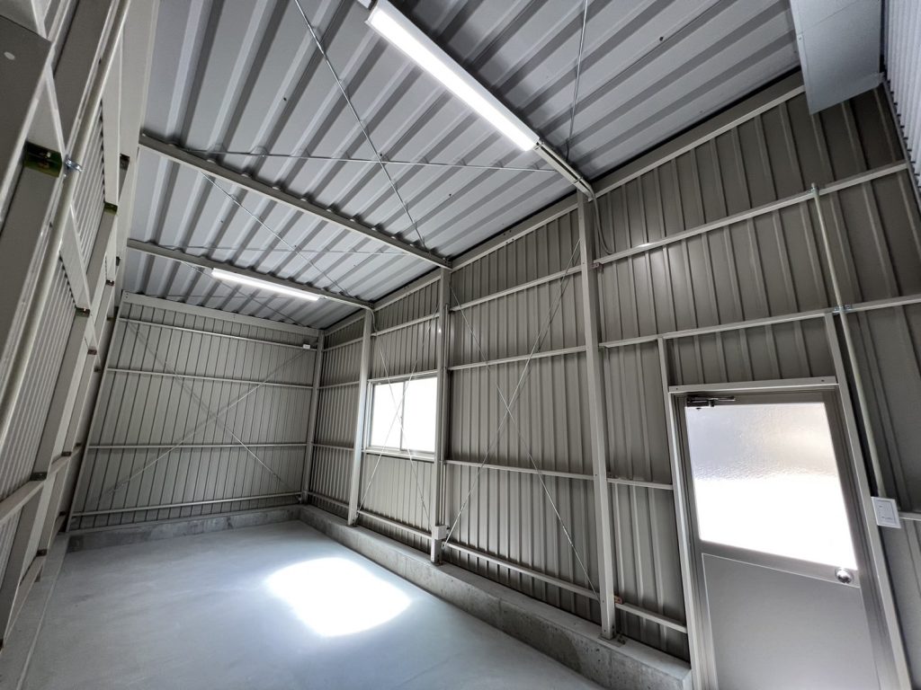 Interior of a Kakuichi steel garage kit at assembly stage — bare metal frame, corrugated walls and concrete floor prior to conversion fit-out