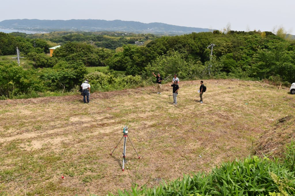 Architects and survey team on cleared Vista Wellmina Villa land parcel, Awajishima, during pre-design site assessment with survey equipment