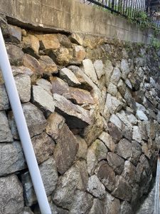 Bulging dry-stone retaining wall showing structural deformation and collapse risk during pre-acquisition site assessment in Japan